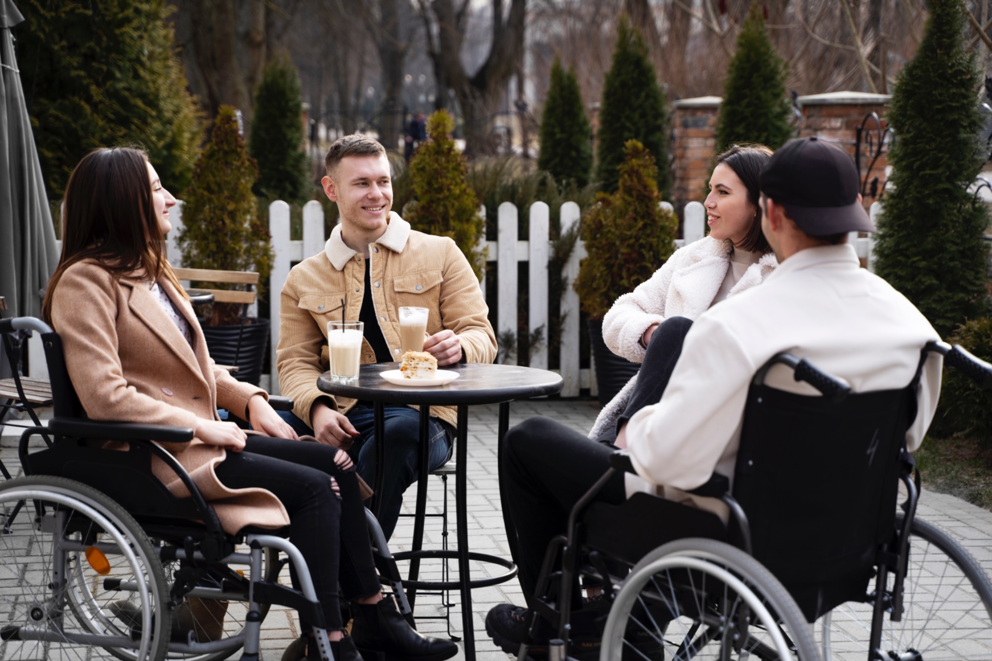 Friends dining together at an outdoor café, including a wheelchair user seated at the table